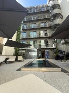 a building with a pool in front of a building with umbrellas at Hotel Leev Miromesnil & Spa in Paris