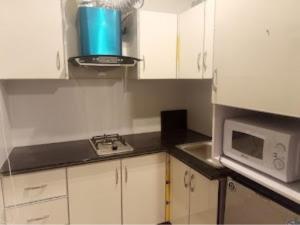 a small kitchen with white cabinets and a microwave at White Ice Cottages in Mānsehra