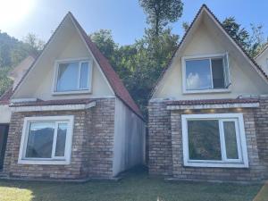 a house with two windows and a brick wall at White Ice Cottages in Mānsehra