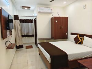 a small bedroom with a bed and a television at Hotel KK Grand in Guntūr