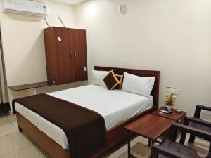 a small bedroom with a bed and a table at Hotel KK Grand in Guntūr +9 photos