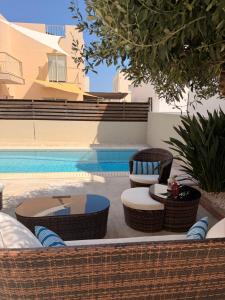 a patio with chairs and tables next to a pool at Pearl House in Paralimni
