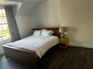a bedroom with a large bed with white sheets and a lamp at Montagu Street in Kettering