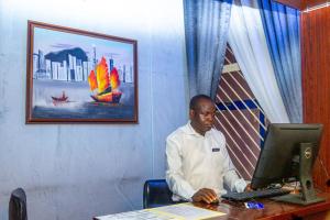 a man sitting at a desk with a computer at Navy Guest House, Kaduna in Kaduna