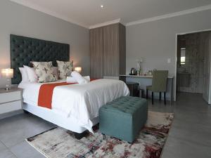 a bedroom with a large bed and a desk and a kitchen at Meloding Guest House in Bela-Bela +27 photos