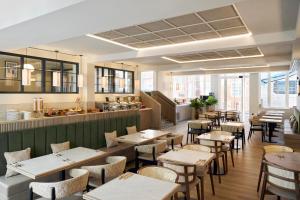 a restaurant with tables and chairs and a kitchen at Four Points Flex by Sheraton London Euston in London