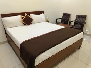 a bed in a room with two chairs and a bedvisor at Hotel KK Grand in Guntūr
