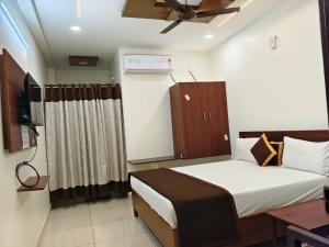 a small bedroom with a bed and a television at Hotel KK Grand in Guntūr