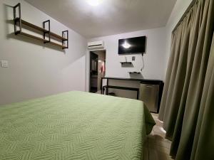 a bedroom with a green bed and a television at Suíte Gute Nacht 3 in Pomerode
