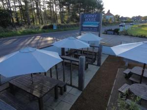 a group of tables with white umbrellas next to a sign at The Dormy House Hotel in Cromer +77 photos