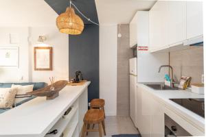 Eine Küche mit weißen Schränken, einem Spülbecken und einem Hocker in der Unterkunft BeGuest Tiny Azure Apartament in Parede