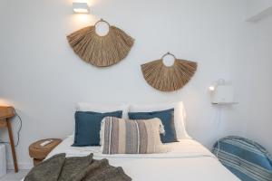 Ein Schlafzimmer mit einem Bett mit blauen Kissen und Strohhüten an der Wand in der Unterkunft BeGuest Tiny Azure Apartament in Parede