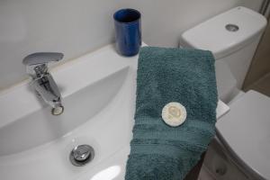 Auf einem Waschbecken im Badezimmer liegt ein grünes Handtuch. in der Unterkunft BeGuest Tiny Azure Apartament in Parede + 6 Fotos