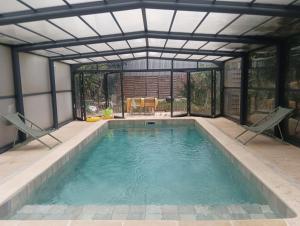 a swimming pool with a metal roof and a swimming poolvisor at Charming House with Private Pool Near Paris - Maison du Bonheur in Gournay-sur-Marne