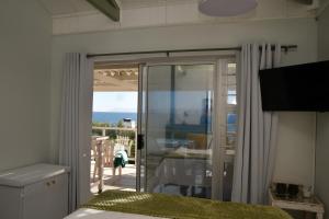 a bedroom with a sliding glass door with a view of the ocean at Amazing Grace B&B in Gansbaai