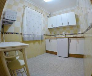 una pequeña cocina con armarios blancos y fregadero en Apartamentos Niña de Oro, en Torremolinos