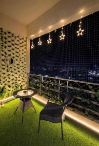 a balcony with a table and a chair and lights at GRiK STAY in Greater Noida