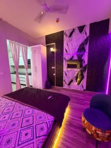 a bedroom with purple lighting and a bed and a chair at Novastay in Greater Noida