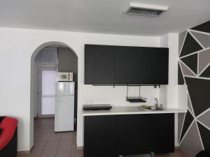 a kitchen with black cabinets and a white refrigerator at Virágos Lakás in Győr