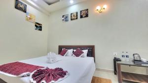 a bedroom with a bed with white sheets and pictures on the wall at Hotel Adarsh in Khagaul