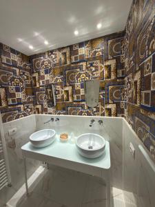 a bathroom with two sinks and a mosaic wall at Hotel Montreal in Florence