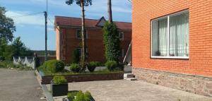 a red brick house with a window and some bushes at Кафе Готель Люкс in Tsarivka +7 photos