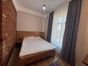 a bedroom with a bed and a brick wall at Beypil Place in Kochkorka