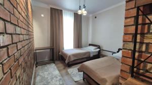 a hotel room with two beds and a brick wall at Beypil Place in Kochkorka