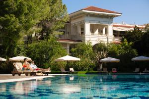 two people sitting on chairs next to a swimming pool at Ali Bey Resort Sorgun in Side