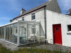 a house with glass doors and a table in front of it at Glenmore Cottage - Waterville in Waterville
