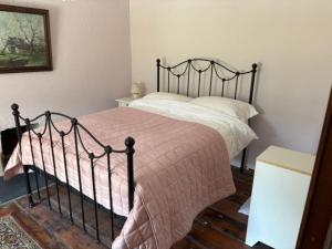 a bedroom with a black bed with a pink blanket at Glenmore Cottage - Waterville in Waterville
