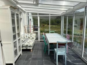 a screened in porch with a table and a couch at Glenmore Cottage - Waterville in Waterville