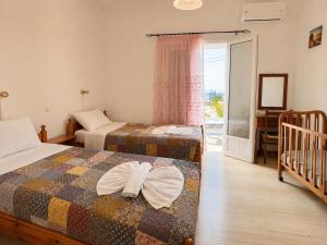 a room with two beds and a crib in it at Eftichia Apartment in Roda