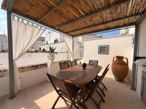 a wooden table and chairs on a patio with a vase at Casa Ulivo in Ostuni