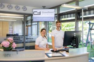 a man and woman standing in front of a desk with a computer at GenoHotel Baunatal in Baunatal