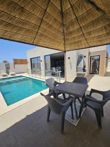 a patio with a table and chairs next to a pool at Villa SAM in Fafou