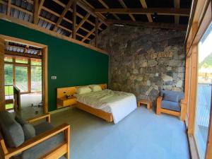 a bedroom with a bed and a stone wall at Lavender Resort Naran in Naran
