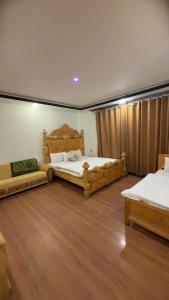 two beds in a room with wooden floors at Multiple Hotels in Malam Jabba Swat in Malam Jabba