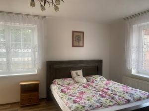 a bedroom with a bed with a floral comforter and two windows at Rodinný dům Na Sibiři in Ledeč nad Sázavou