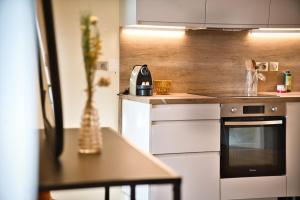 a kitchen with an oven and a table with a vase at Elegant apartment with balcony - Maison Comte in Uzès