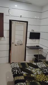 a room with a door and a desk and a bed at Hotel Atithi - Oposite Shreeji Hospital in Rajkot