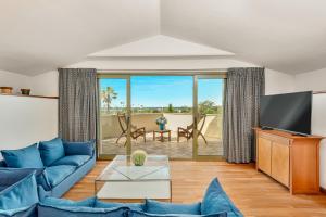 a living room with a blue couch and a tv at Hotel Villa Undulna - Terme della Versilia in Cinquale