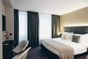 a hotel room with a bed and a chair at Hôtel des Voyageurs Boutique in Lausanne