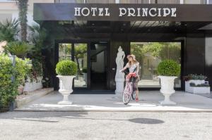 uma mulher a andar de bicicleta em frente a um edifício em Hotel Principe em Alba Adriatica