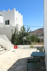 a table and chairs on a patio with a white building at Lyra Apartments Tilos in Livadia