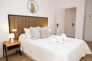 a white bedroom with a large bed and a table at Cazorla a tus pies, en pleno centro con parking in Cazorla