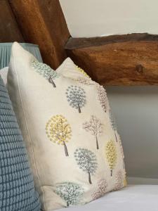 a pillow with trees on it sitting on a bed at Stunning stone cottage on Bath's doorstep in Box