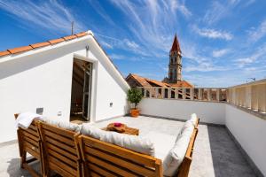 a balcony with a couch and a clock tower at Villa Mater in Trogir