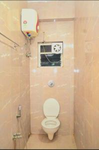 a small bathroom with a toilet and a window at Galaxy Stellar Suites in kolkata