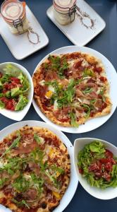 a table with four plates of pizza and a salad at Les Clos De La Vigne in Vals-les-Bains